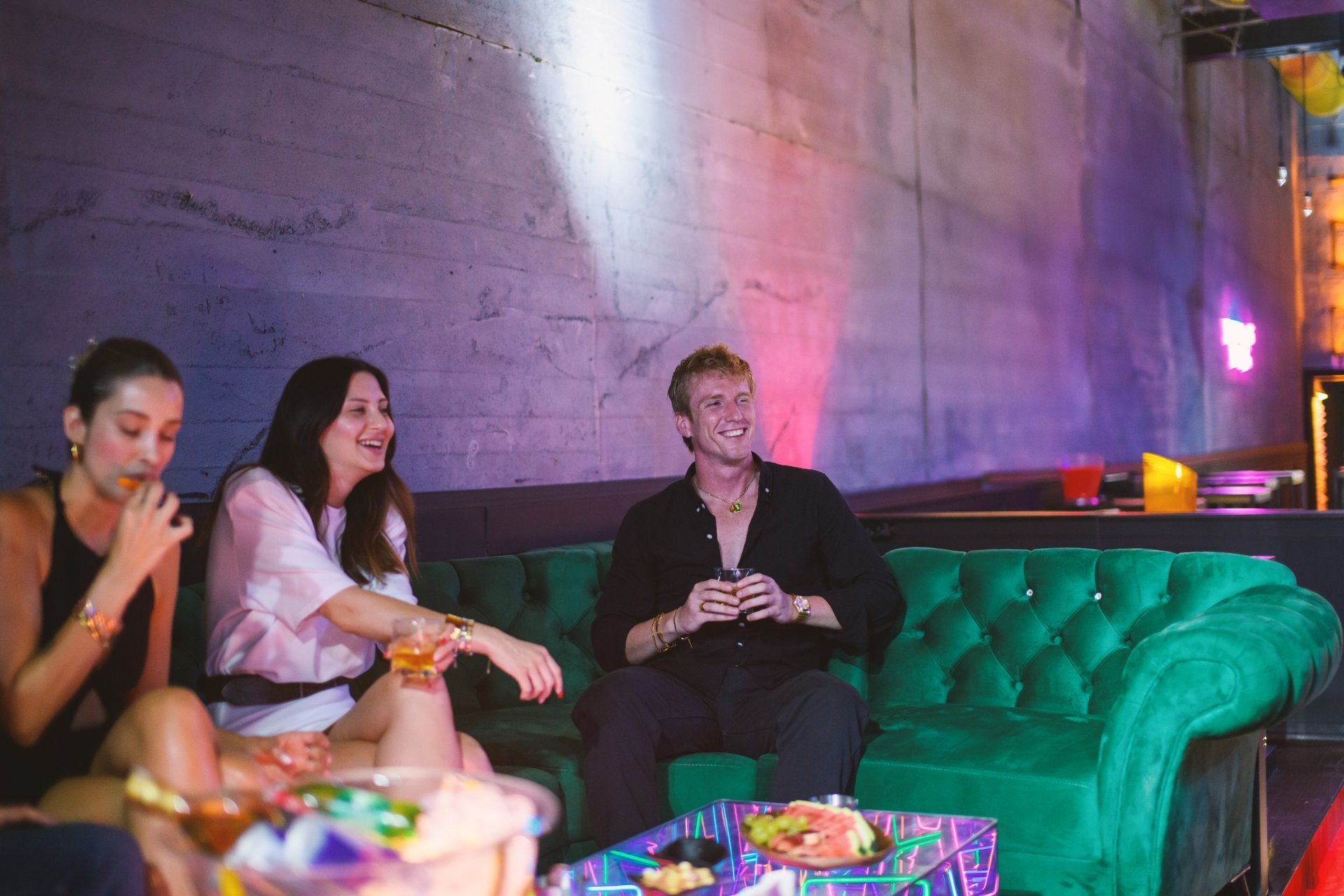 Young group lounging in VIP area enjoying drinks at night